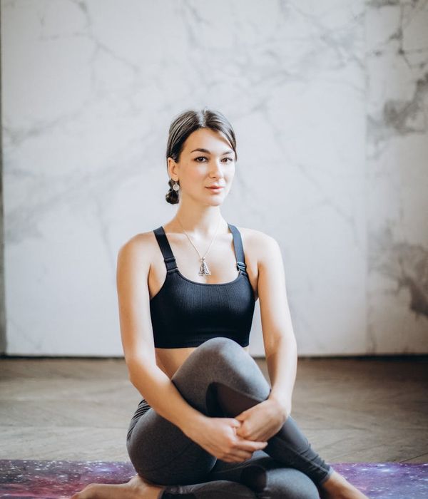 Woman in a serene yoga pose against a calm background.